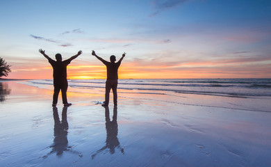 two men at the beach during beautiful sunset. 