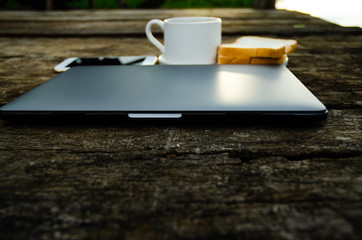 Coffee, bread and notebook computers placed on wooden floor in the morning of the river.Breakfast set on wooden floor in the morning.Breakfast with coffee and bread.Do not focus on objects.