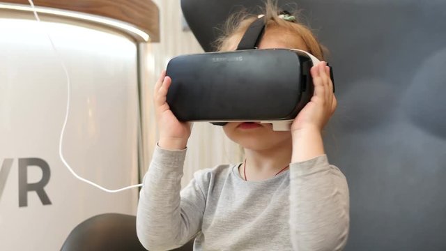Little child kid girl watching animation film through 3D virtual reality glasses