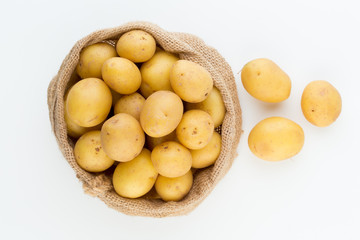 Sack of fresh raw potatoes on wooden background, top view
