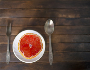 pink grapefruit on a white plate and Cutlery

