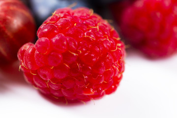Close-up arrangement mixed, assorted berries including blackberries, strawberry, blueberry, raspberries and fresh leaf on white