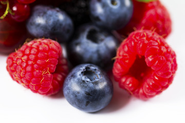Close-up arrangement mixed, assorted berries including blackberries, strawberry, blueberry, raspberries and fresh leaf on white