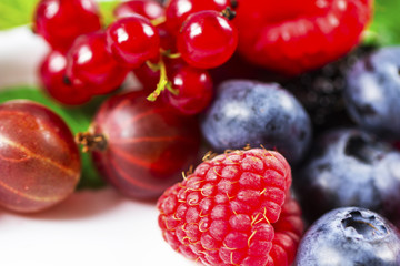 Close-up arrangement mixed, assorted berries including blackberries, strawberry, blueberry, raspberries and fresh leaf on white