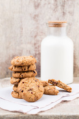 Chocolate oatmeal chip cookies with milk on the rustic wooden table.