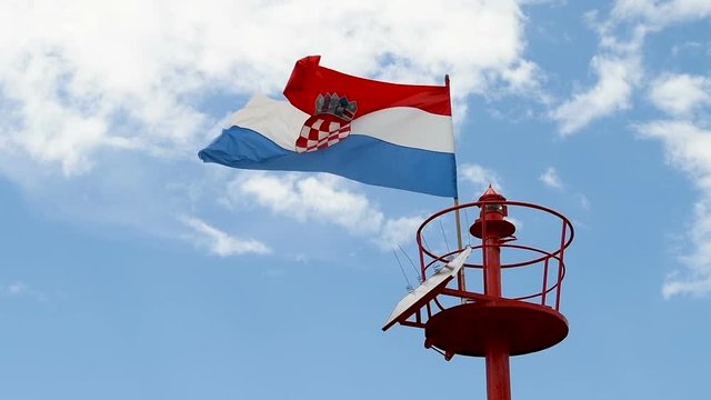 Lighthouse, light beacon pole with flying Croatian flag in daylight, slow motion 4x, close up shot