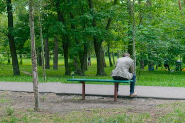 A lonely man is sitting on a bench in the park.