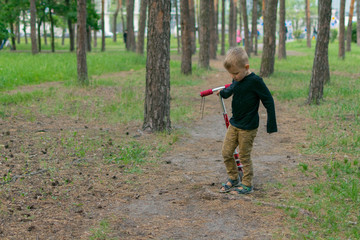A little boy is riding a scooter along the park path.