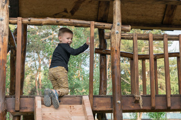 A little boy is climbing a children's hill in the park in the summer. The child is 3-5 years old. Active rest on a children's playground.
