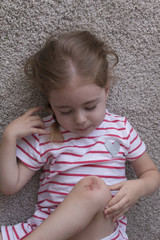 Fototapeta premium Close-up portrait of girl with a knee injury lying on floor