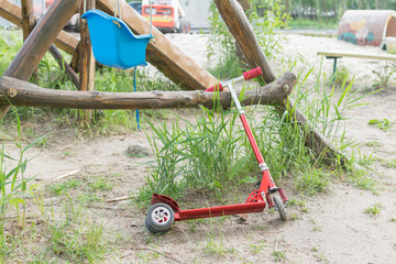 A children's red scooter left in the playground.
