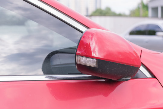 A Folded Side View Mirror On A Red Car.