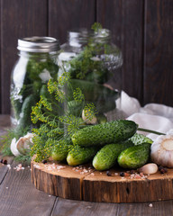 Preserved cucumbers in glass jars with garlic and dill on table