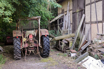 Old farm tractor parked in front of an old timber-framed building