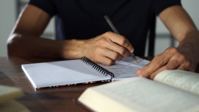 Close-up Hands writting in a notebook on the table. Student studying, education, university concept