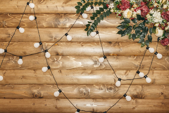 Wooden wall decorated by electric garland and flowers. Decoration for wedding or Reception. Copy space