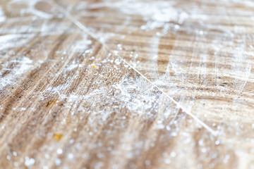 Closeup of wooden table surface in kitchen with messy dirty cooking preparation bakery dusted with flour background