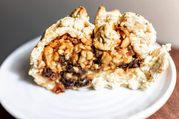 Closeup of large slice piece of apple pie cake, fruit filling and healthy golden crust with cinnamon on white plate, raisins