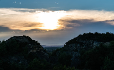 zwei berge, die in der Mitte den Blick auf die Ebene freigeben, über ihr die untergehende Sonne