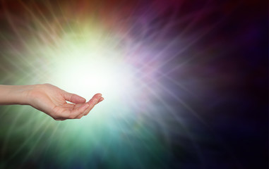Energy healer with open hand - female hands sensing life force energy with open palm inside a multicoloured ball of light with copy space
