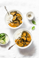 Roasted aubergine curry with rice on a light background, top view. Indian vegetarian cuisine. Flat lay