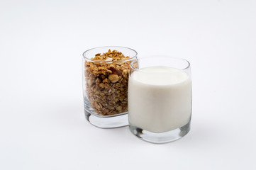 A glass full of milk and a glass full of muesli on a white background