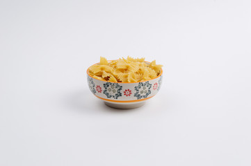 Ceramic bowl full of farfalle pasta and rotini on white background
