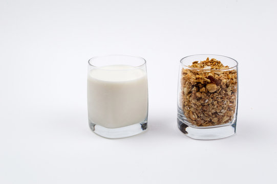 A glass full of milk and a glass full of muesli on a white background