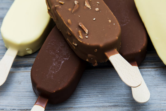Chocolate ice cream lollies on a wooden background.