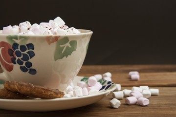 Beautiful vintage cup of homemade hot chocolate or cocoa with marshmallows, wooden table and black background. Warm sweet drink. Copy space.