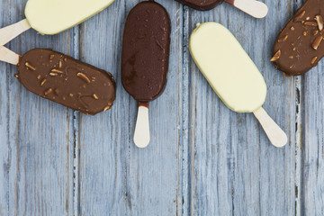 Chocolate ice cream lollies on a wooden background.