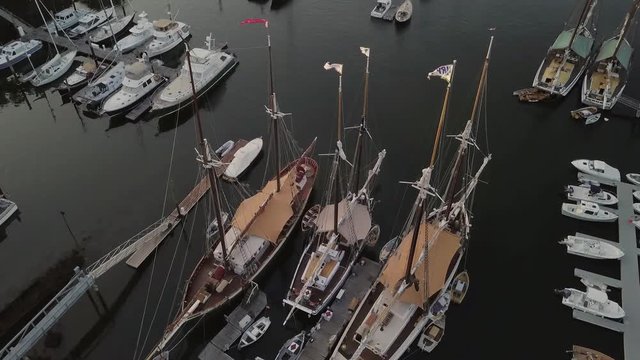 Aerial footage of an early morning flight over Camden harbor featuring many tall masted yachts and the Curtis Island lighthouse.