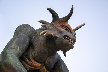 Тhe head of the awful horned demon against the background of the blue sky