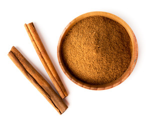 Cinnamon sticks and wooden plate with ground cinnamon on a white. The view from the top.