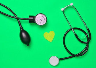 Cardiological concept. Medical monometer, stethoscope, decorative heart on a yellow background. Top...