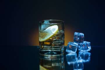Ice and brandy or cognac in glass with slice of lemon