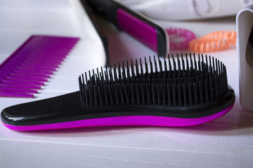 Hair care instruments. Beauty salon. Hair care tools on the dark blue wooden background. Hair Dryer, curling iron, combs and bright spiral scrunchies.
