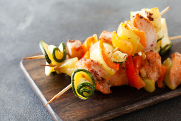 Barbecued turkey kebab with pepper and zucchini on wooden board