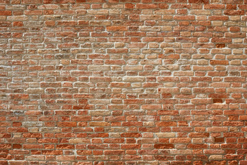 Old red brick wall texture background in sunlight with shadows