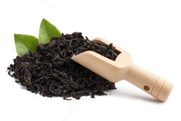 Dry black tea with green leaves and a wooden scoop, isolated on white background