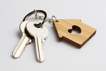 House keys with house shaped keychain on white background
