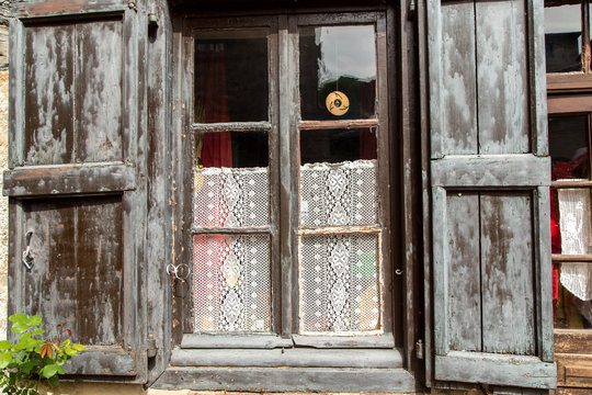 Leaded Glass Window with Lace Curtain and Peeling Gray-Painted Shutters in Perouges, France