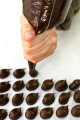 WOMAN HAND PREPARING CHOCOLATE TRUFFLES AGAINTS WHITE BACKGROUND