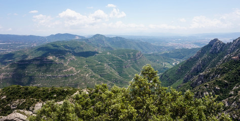 Obraz premium A beautiful view of the multi-peaked mountain range from high above, Montserrat, near Barcelona, Spain. Shadows of the clouds lie on a mountain's peak.