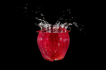 Red vibrant fresh apple splashing into water