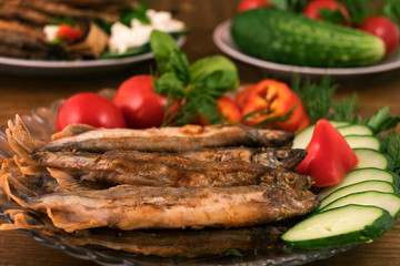Whole fried fish with garnish of fresh vegetables, basil leaves and dill.