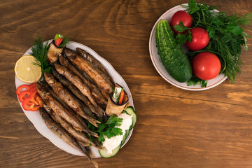 Small fish, whole fried in oil until crispy brown with whole and chopped vegetables with a slice of lemon and stuffed eggplant.