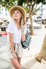 Beautiful young woman in summer hat walking in the city.