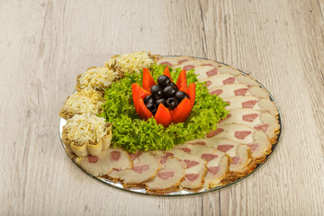 Meat sliced on a mirror dish decorated with verdure.