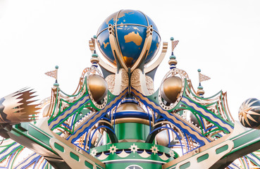 Carousel at a carnival or festival at sunset. Decorative ornate globe, stars and flags at an amusment park.